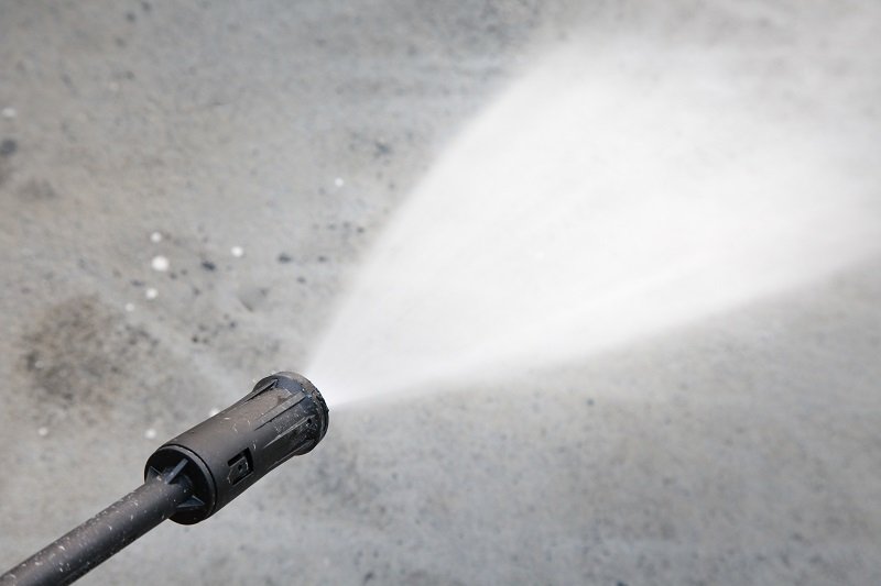 Water hose spray gun washing his cement floor